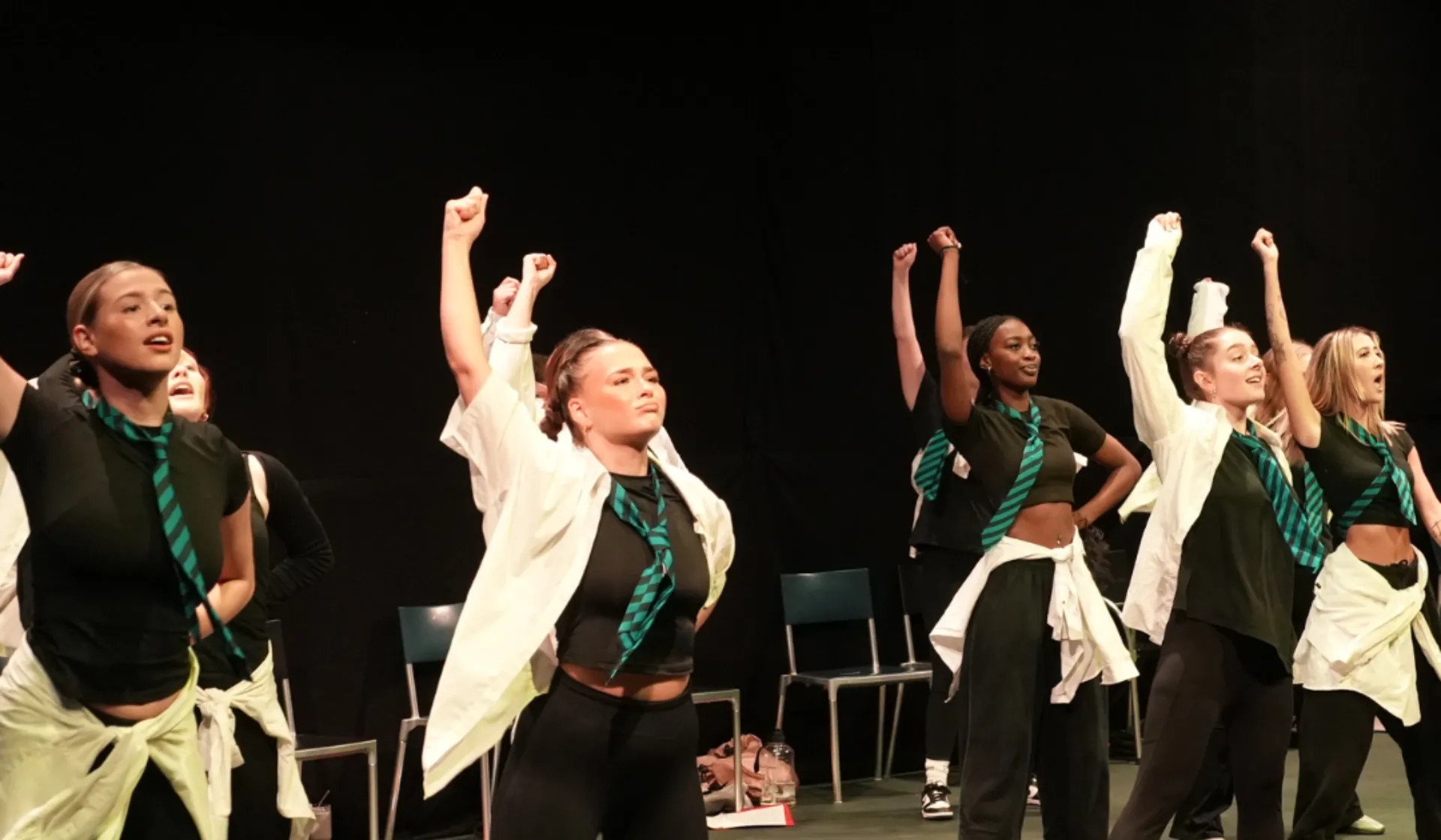 The cast of Day 1 big school with their hands raised