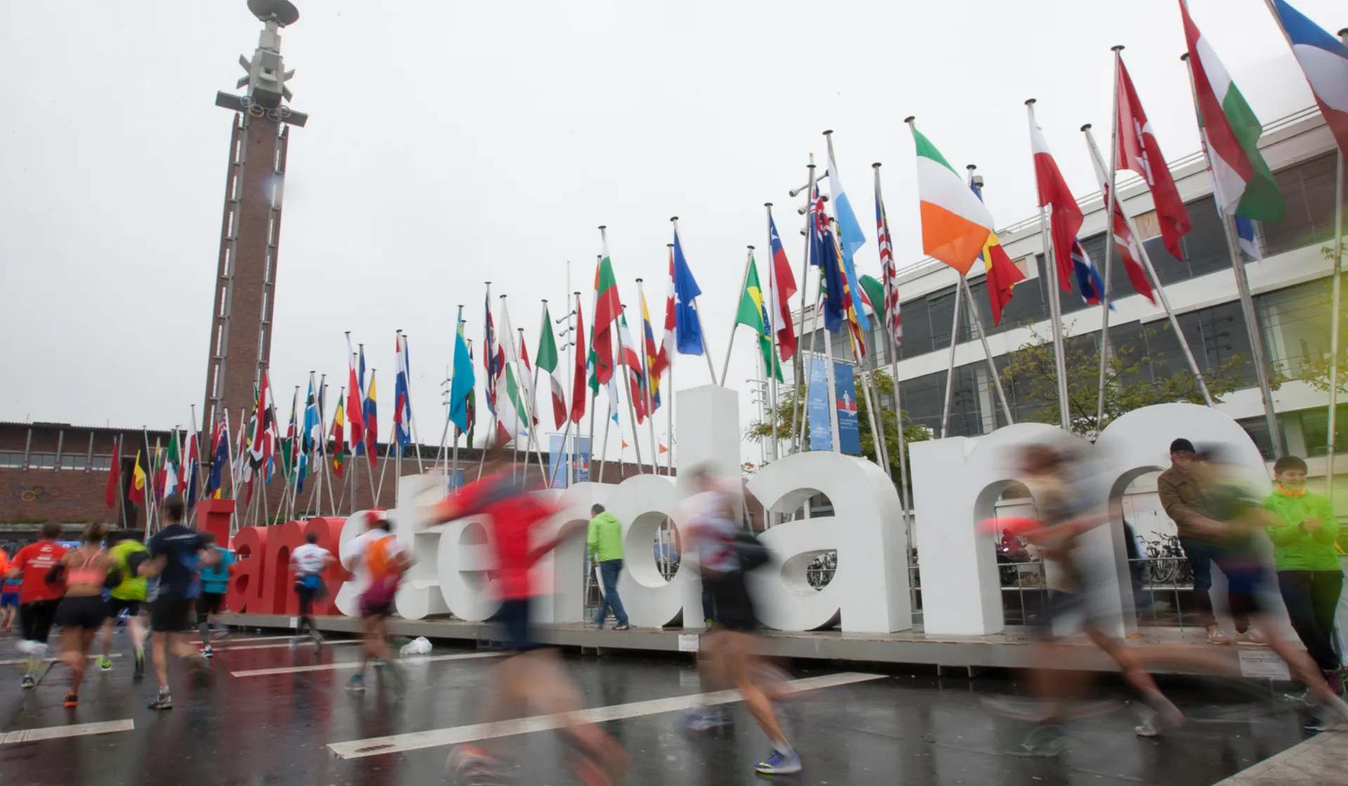 Runners run past an Amsterdam sign