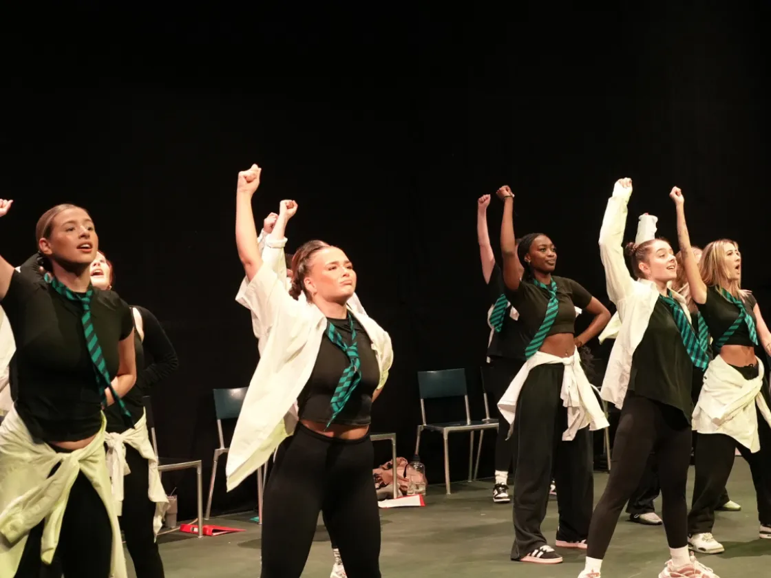 The cast of Day 1 big school with their hands raised