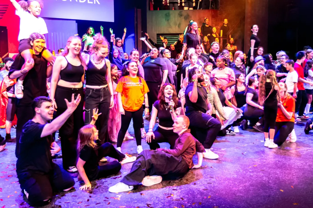 LArge group of young people on pink washed stage