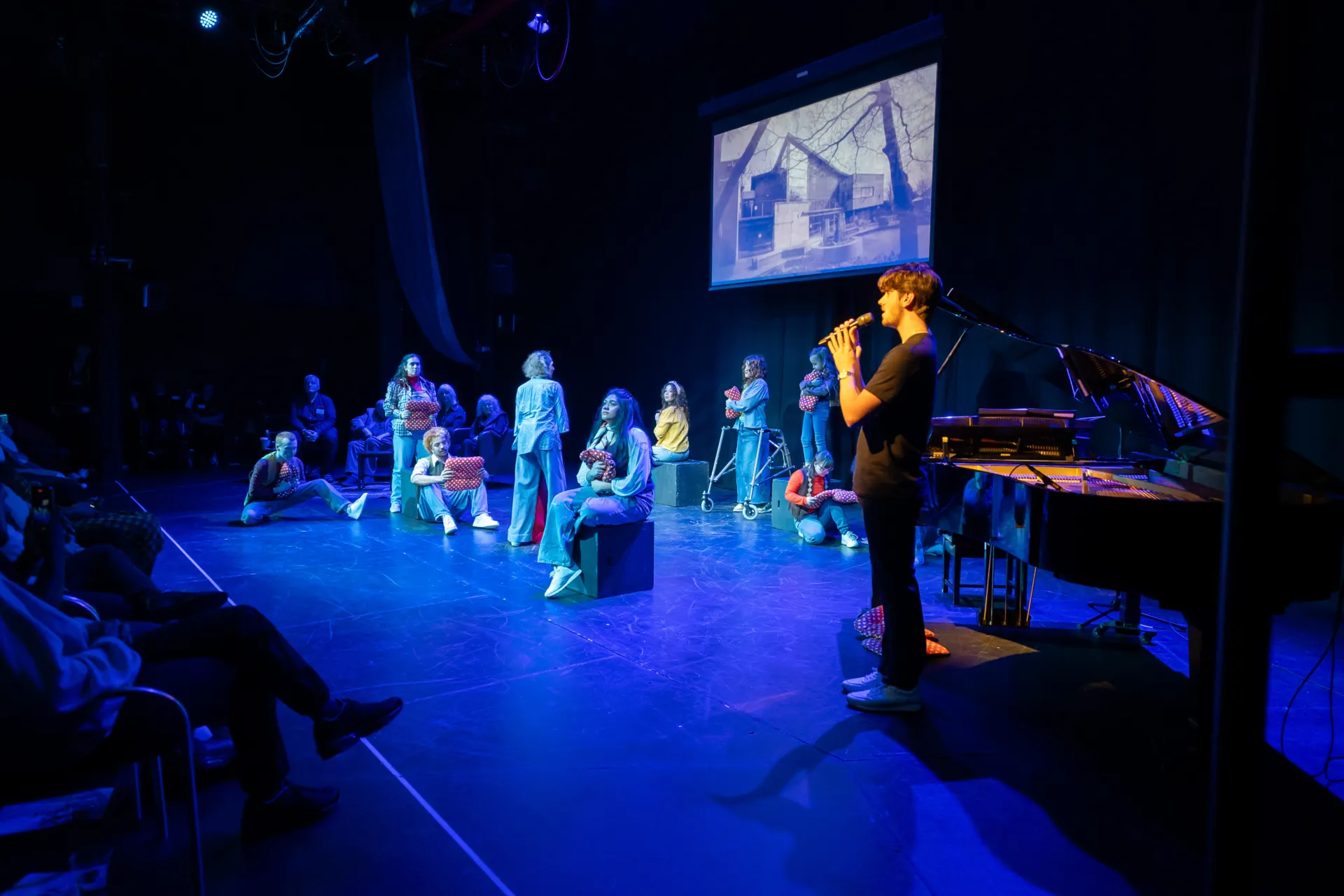 Chickenshed's young people performing 'home' at the Place of Our Own event. A picture of the original Chickenshed is projected above.