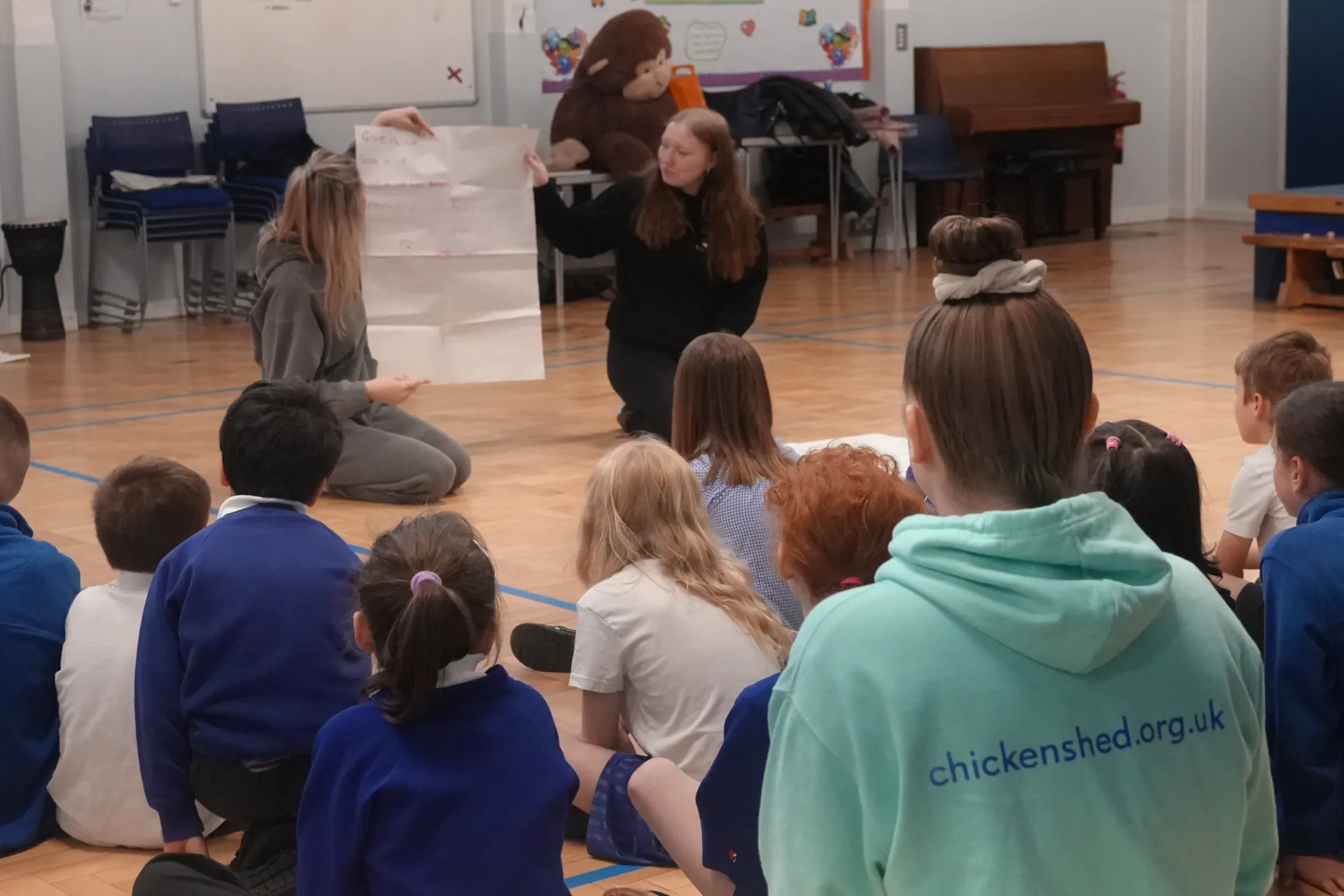 2 students holding up lyrics to a song, teaching the children at Livingstone Primary school
